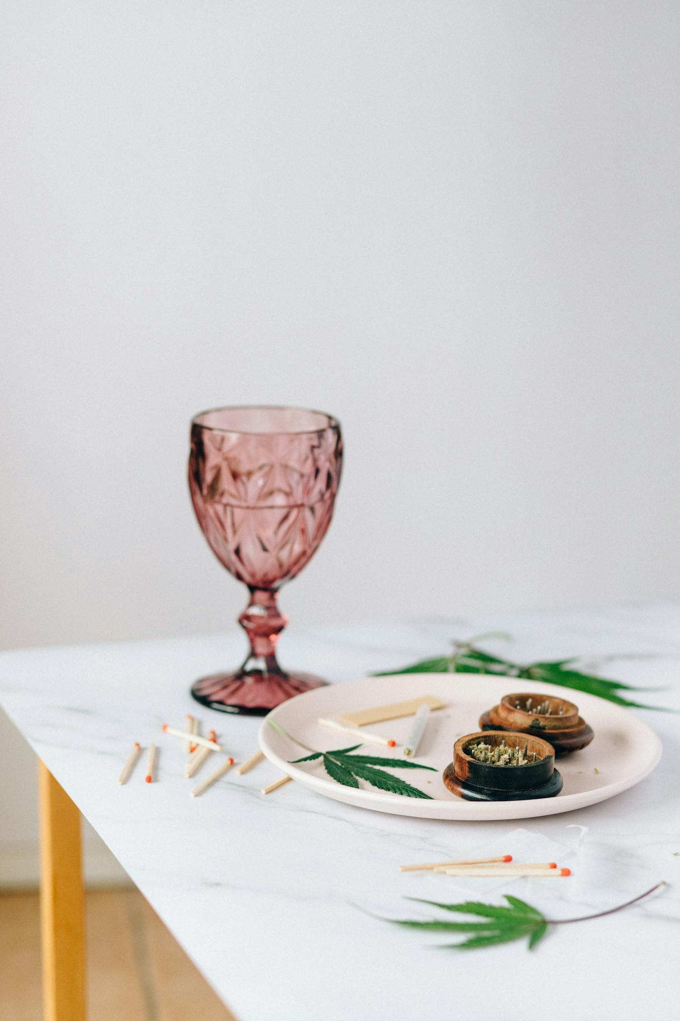 Stylish setup featuring cannabis on a marble table with a wine glass and matches.